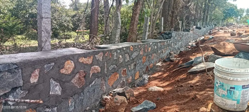 All stone boundary wall with granite pillars