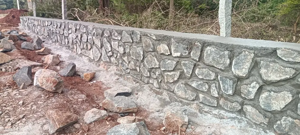 Stone retaining wall with concrete cap along roadside